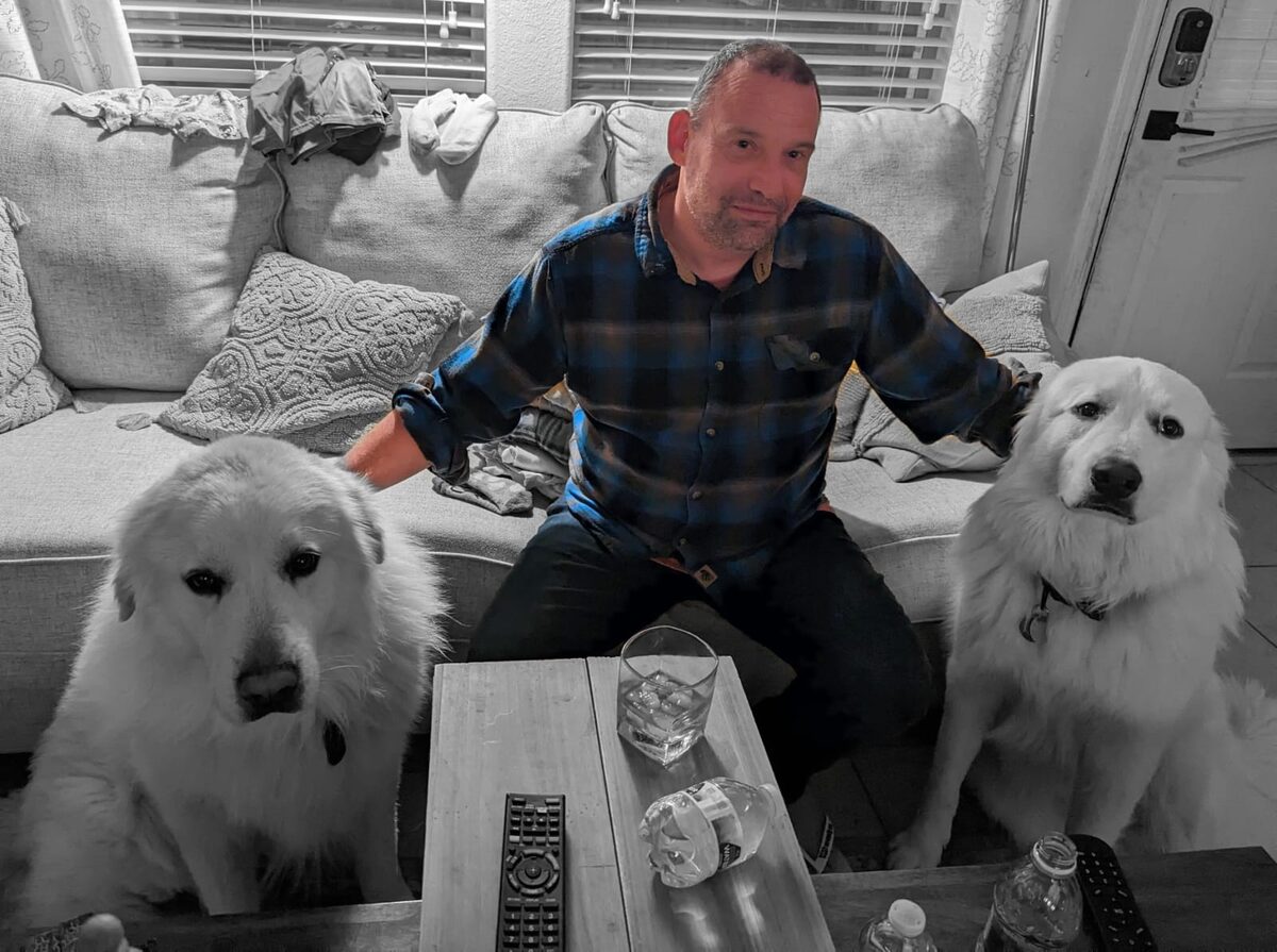 Ronnie sitting with his two Great Pyrenees dogs